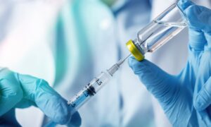 Doctor with latex gloves filling up a syringe with liquid.